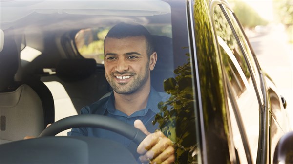 Renault Service Mécanique - Un homme brun sourit au volant de sa voiture